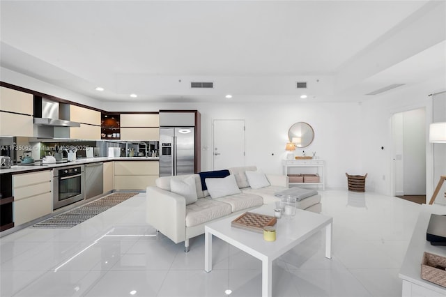 tiled living room featuring a tray ceiling and sink