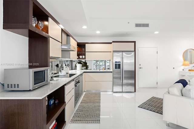 kitchen featuring light tile patterned floors, stainless steel appliances, sink, and wall chimney exhaust hood