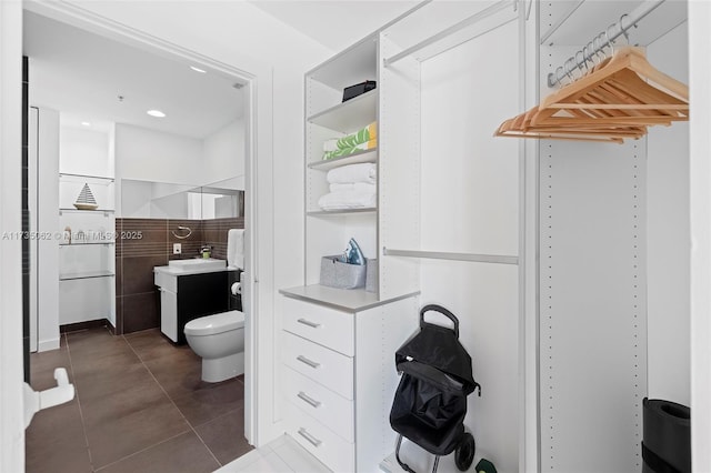 bathroom with tile patterned floors, toilet, a shower, tile walls, and vanity