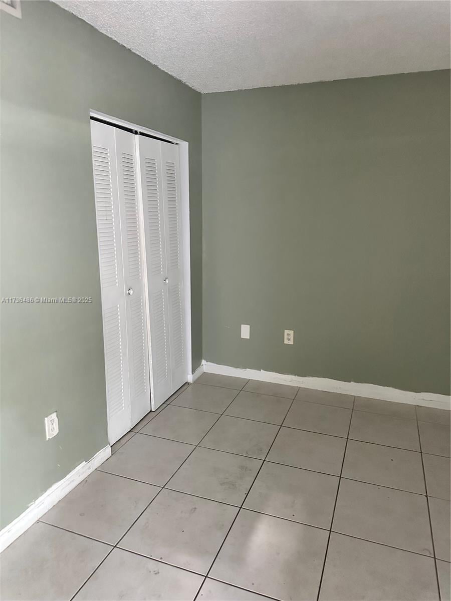 unfurnished bedroom with light tile patterned floors, a closet, and a textured ceiling