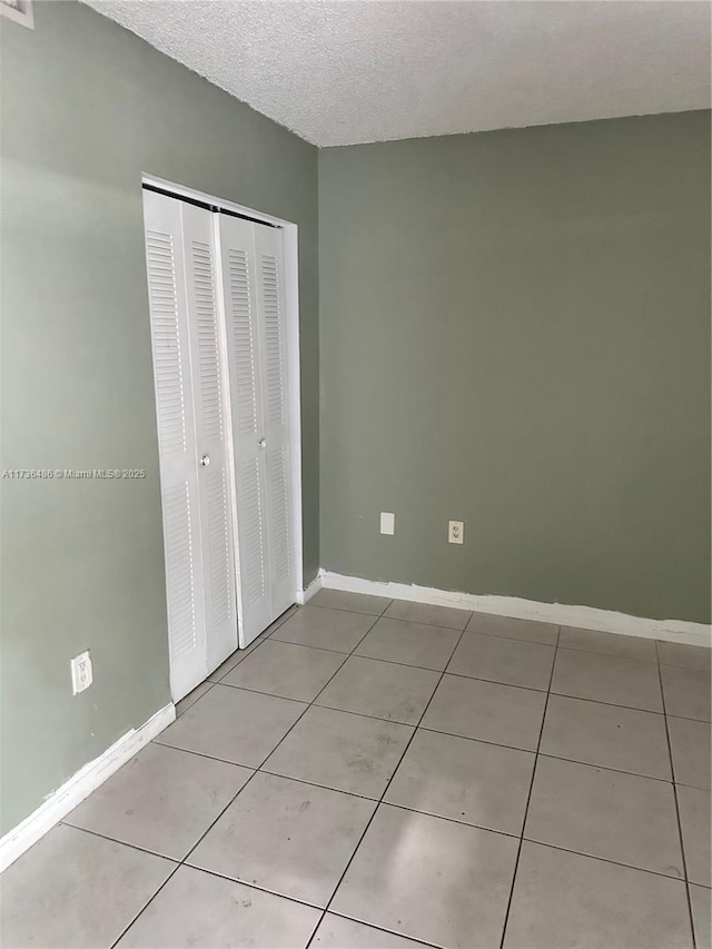 unfurnished bedroom with light tile patterned floors, a closet, and a textured ceiling