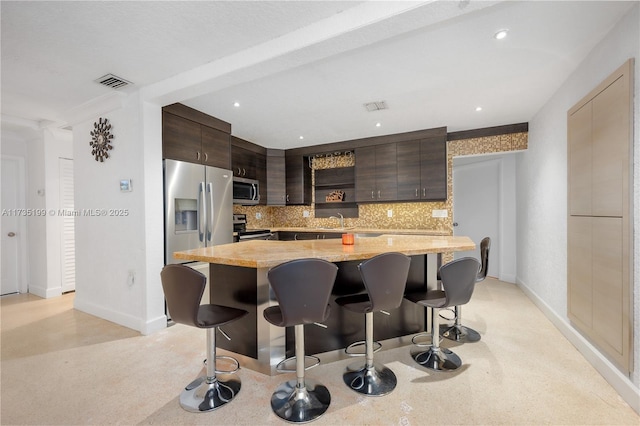 1498 NE 39th St, Oakland Park, FL 33334 - kitchen featuring stainless steel appliances, dark brown cabinets, a breakfast bar area, baseboards, and recessed lighting