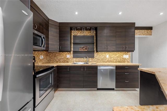 1498 NE 39th St, Oakland Park, FL 33334 - kitchen with stainless steel appliances, a sink, dark brown cabinets, backsplash, and light stone countertops