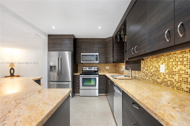 1498 NE 39th St, Oakland Park, FL 33334 - kitchen with stainless steel appliances, decorative backsplash, a sink, dark brown cabinets, and light stone counters