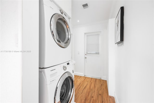 1498 NE 39th St, Oakland Park, FL 33334 - laundry area with stacked washing machine and dryer, light wood-style flooring, crown molding, and baseboards