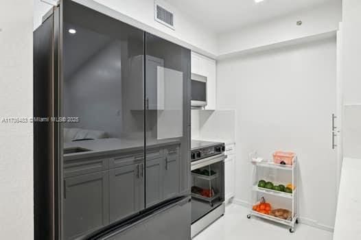 kitchen with stove, black refrigerator, and gray cabinetry