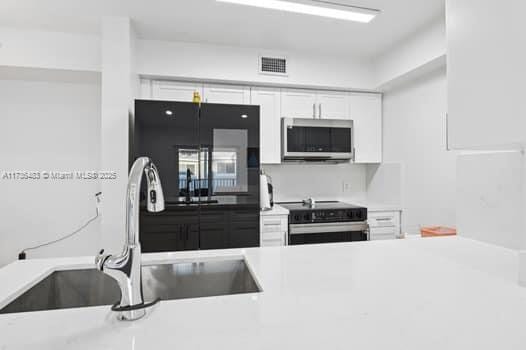 kitchen with appliances with stainless steel finishes, sink, and white cabinets