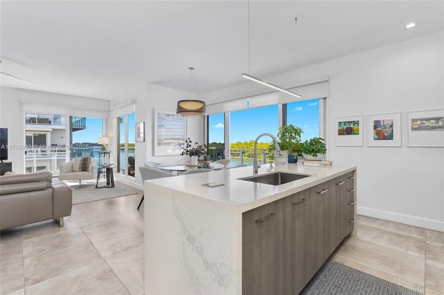 kitchen featuring a healthy amount of sunlight, a kitchen island with sink, and sink