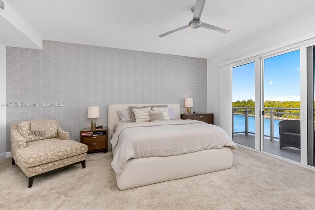 carpeted bedroom featuring a water view, access to exterior, and ceiling fan