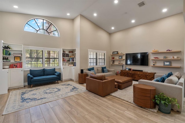 living room featuring a towering ceiling and light wood-type flooring