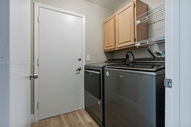 washroom featuring cabinets, washing machine and clothes dryer, and light wood-type flooring