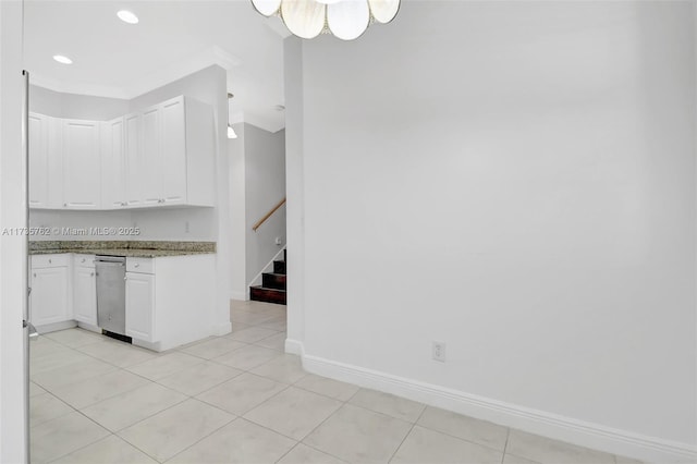 kitchen featuring stone counters, white cabinetry, light tile patterned floors, and crown molding