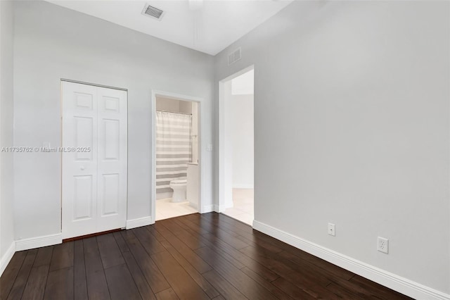 unfurnished bedroom with wood-type flooring, connected bathroom, and a closet