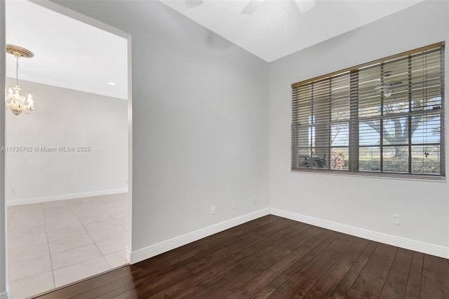 spare room featuring ceiling fan with notable chandelier, vaulted ceiling, and hardwood / wood-style floors