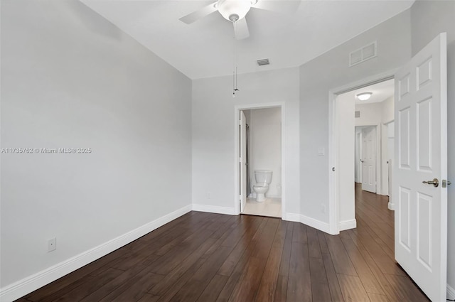 unfurnished bedroom with ensuite bathroom, dark wood-type flooring, and ceiling fan