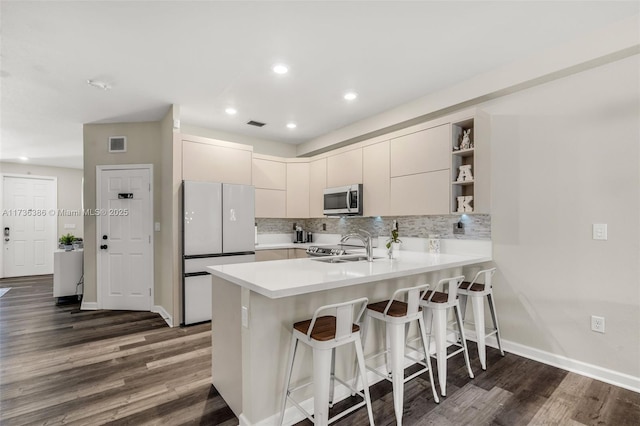18330 NW 91st Ct Unit 18330, Hialeah, FL 33018 - kitchen featuring stainless steel appliances, a peninsula, dark wood-type flooring, a kitchen bar, and light countertops