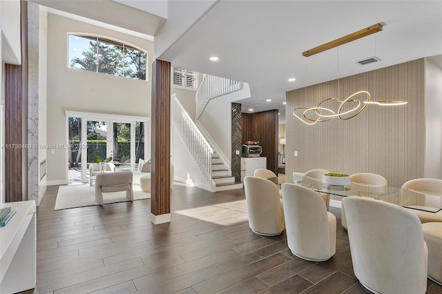 dining area with hardwood / wood-style floors and a towering ceiling