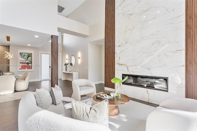 living room with a towering ceiling, a high end fireplace, and hardwood / wood-style floors