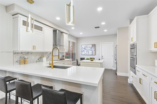 kitchen with white cabinetry, kitchen peninsula, a kitchen bar, and decorative light fixtures