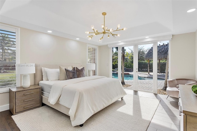 bedroom with multiple windows, access to outside, a raised ceiling, and wood-type flooring