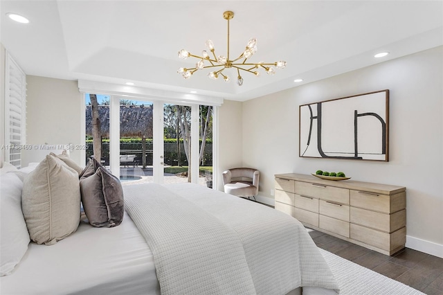 bedroom featuring an inviting chandelier, access to exterior, dark wood-type flooring, and a raised ceiling