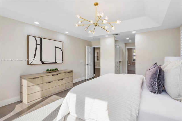 bedroom with an inviting chandelier, a raised ceiling, and light hardwood / wood-style flooring