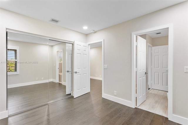 unfurnished bedroom with dark wood-type flooring and a closet