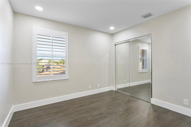 unfurnished bedroom with dark wood-type flooring and a closet