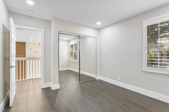 unfurnished bedroom with dark hardwood / wood-style floors and a closet