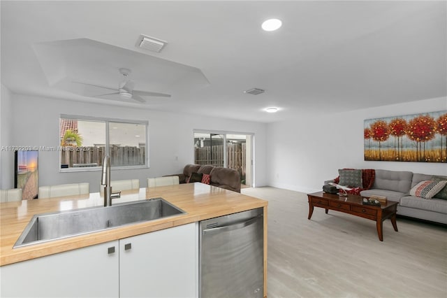 kitchen featuring sink, ceiling fan, white cabinetry, light hardwood / wood-style floors, and stainless steel dishwasher