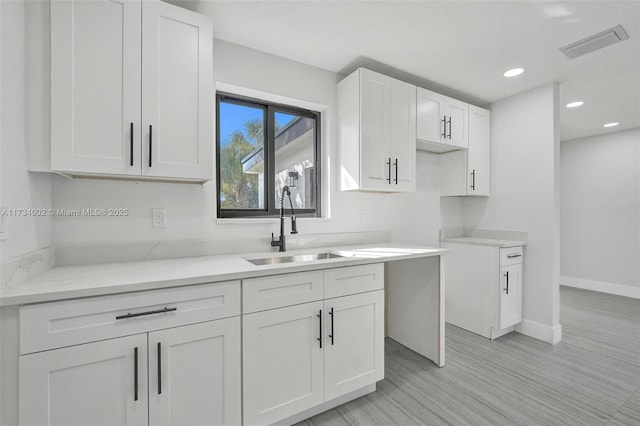 kitchen with sink, light stone countertops, and white cabinets