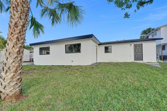212 SW 11th Ave, Dania Beach, FL 33004 - rear view of house with a lawn and stucco siding