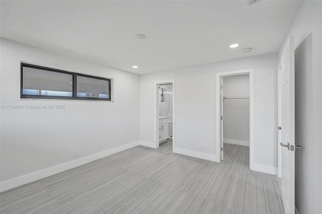 unfurnished bedroom featuring ensuite bath, a spacious closet, and a closet