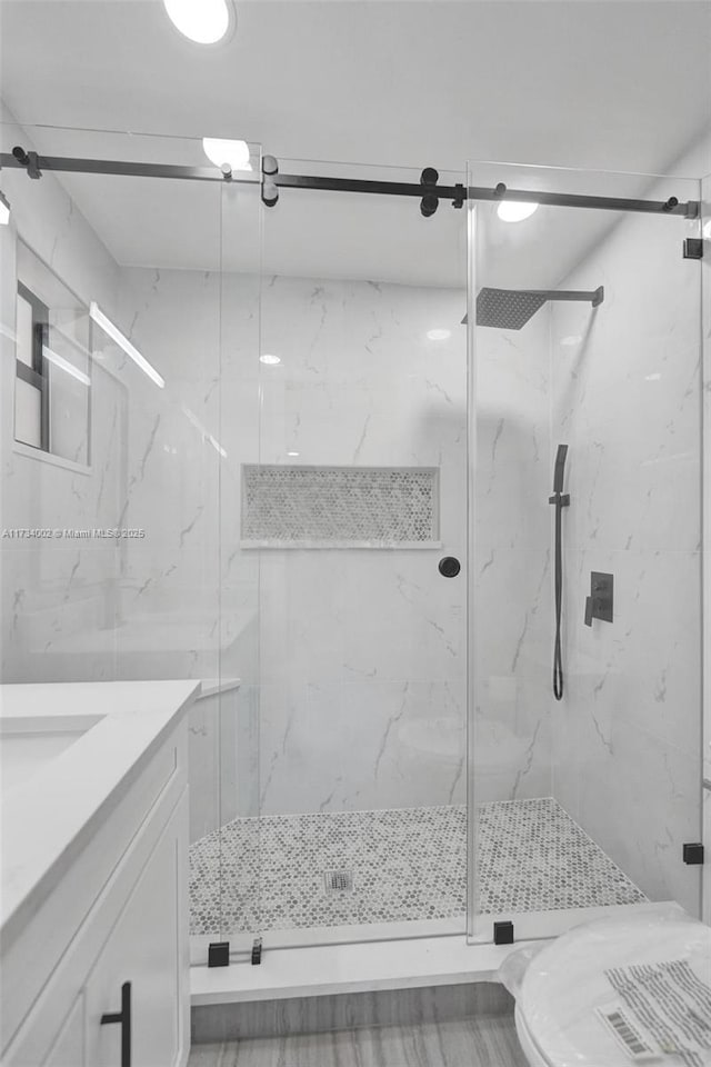 bathroom with vanity, a shower with door, and toilet