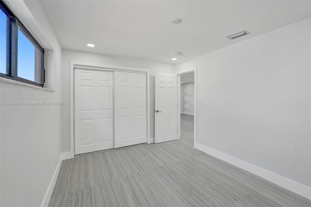 unfurnished bedroom featuring light hardwood / wood-style flooring and a closet