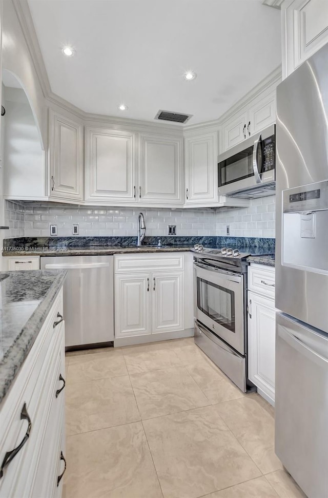 kitchen with sink, white cabinetry, tasteful backsplash, dark stone countertops, and appliances with stainless steel finishes