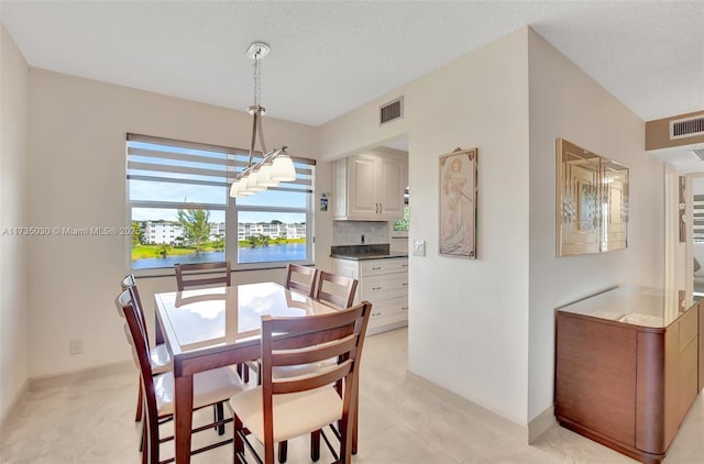 dining area with a water view and a textured ceiling