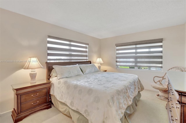 bedroom featuring light colored carpet and a textured ceiling