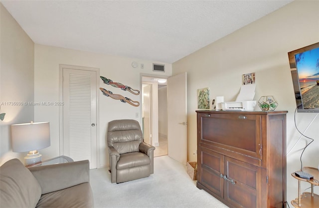 living area with light carpet and a textured ceiling