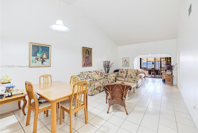 tiled dining space featuring high vaulted ceiling