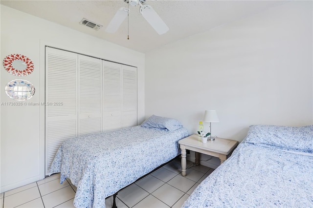 tiled bedroom with ceiling fan and a closet