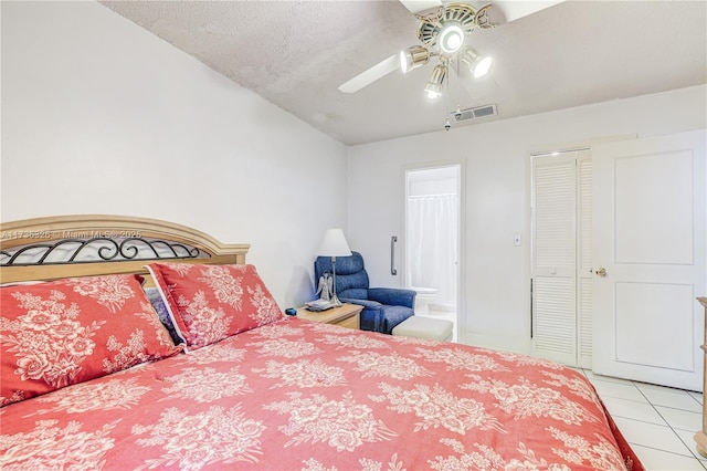 bedroom featuring ensuite bathroom, light tile patterned floors, ceiling fan, a textured ceiling, and a closet