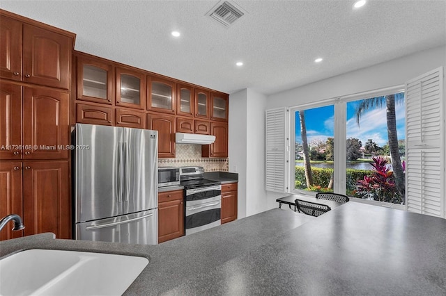 kitchen with stainless steel appliances, sink, a textured ceiling, and backsplash