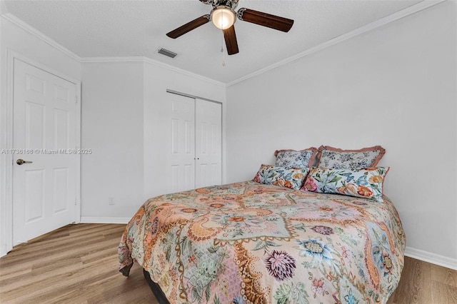 bedroom featuring wood-type flooring, ornamental molding, ceiling fan, and a closet