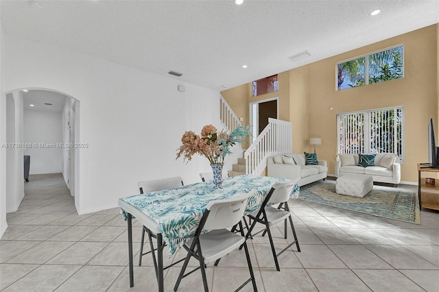 dining area with a high ceiling, light tile patterned flooring, and a textured ceiling