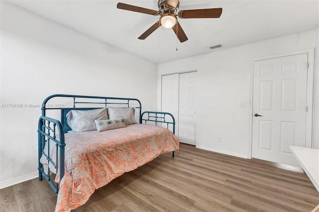 bedroom with hardwood / wood-style floors, ceiling fan, and a closet