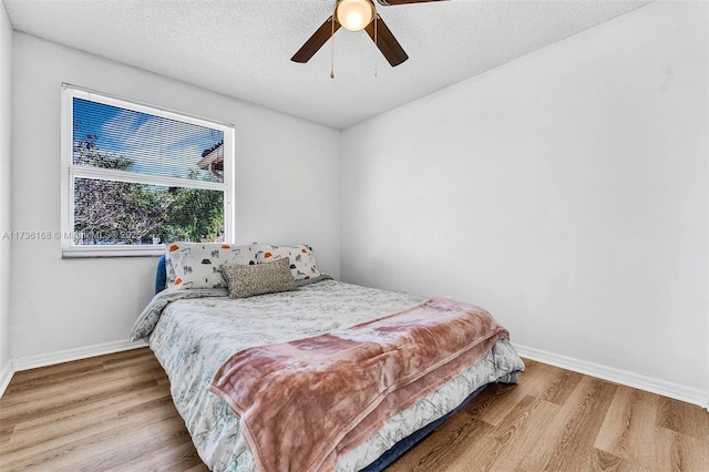 bedroom featuring ceiling fan, a textured ceiling, and light hardwood / wood-style floors