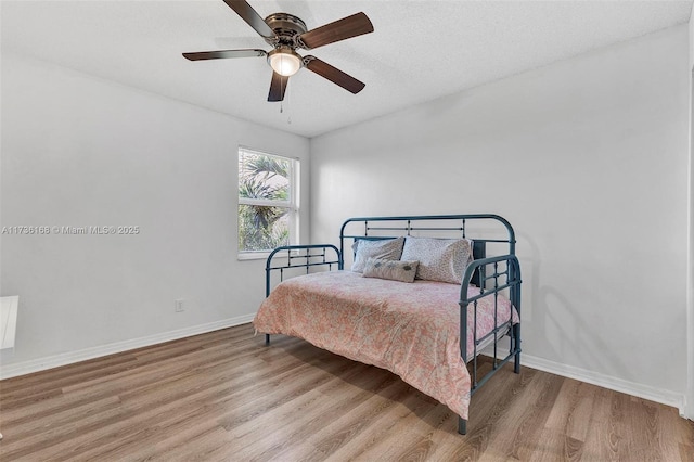 bedroom with a textured ceiling, light hardwood / wood-style floors, and ceiling fan