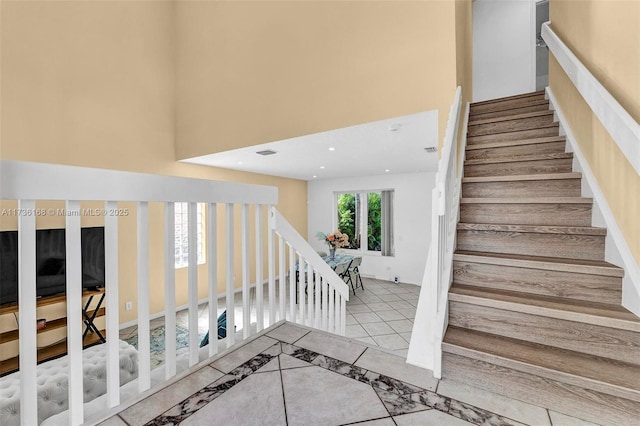 stairway with a towering ceiling and tile patterned floors