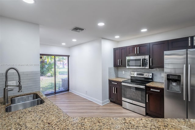 kitchen featuring appliances with stainless steel finishes, light stone countertops, sink, and light hardwood / wood-style flooring